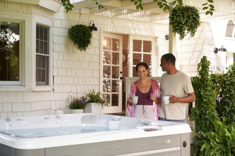 beige hot tub in front of the nice white house with a happy couple